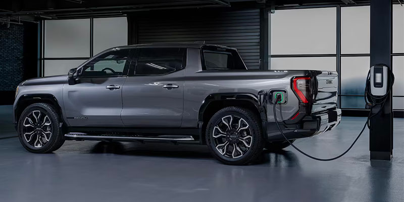 2026 GMC Sierra EV Elevation pickup truck charging in a modern garage in Lone Tree, CO, showcasing its sleek design and electric capability.